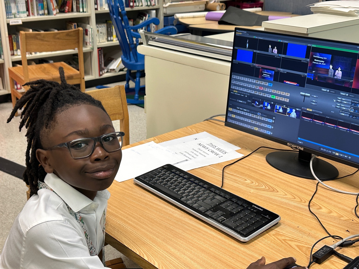 A child sitting at a desk with a computerDescription automatically generated